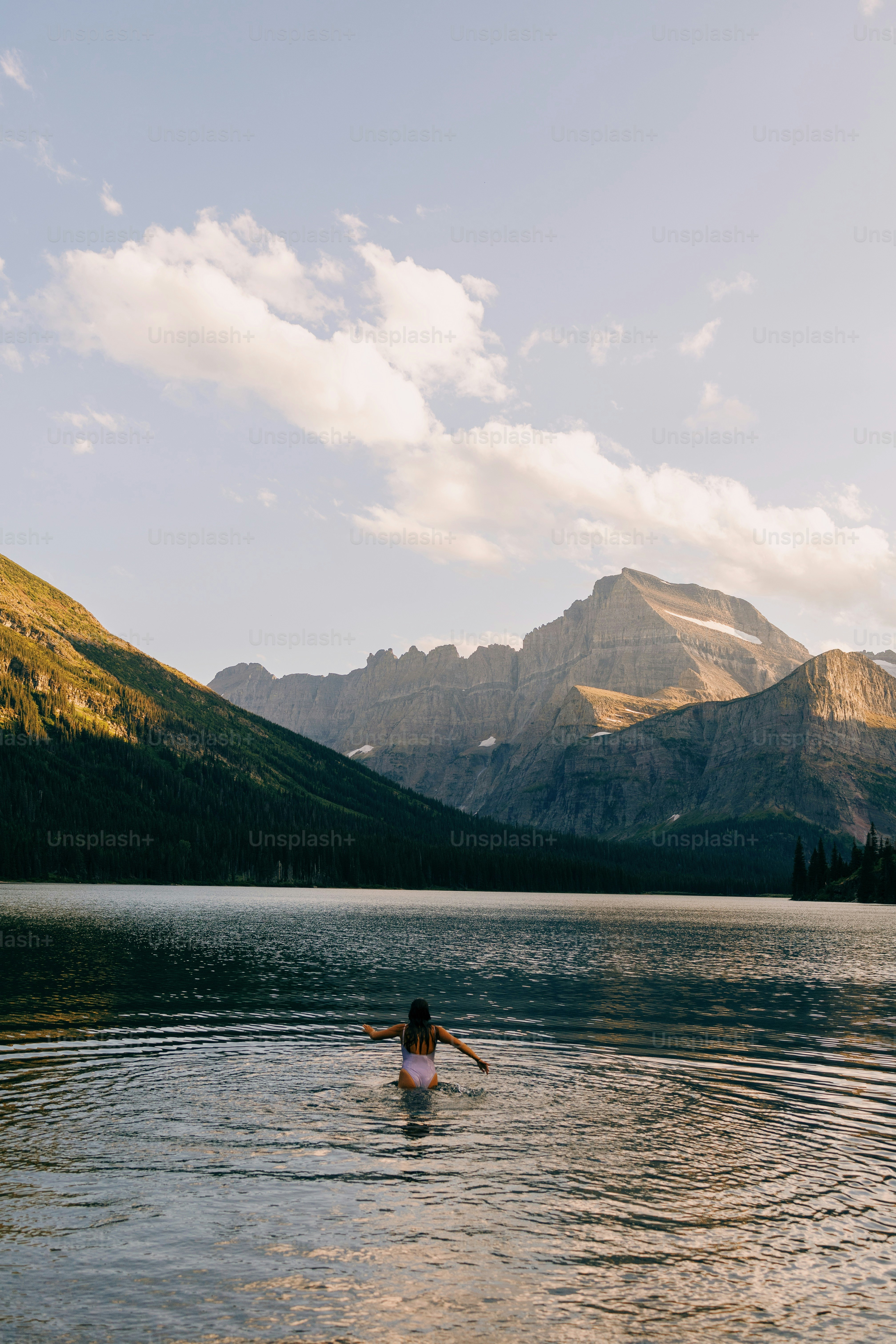 Una persona in uno specchio d'acqua con le montagne sullo sfondo