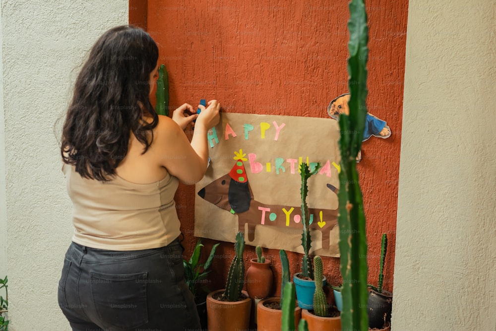 eine Frau, die neben einem Kaktus auf eine Geburtstagskarte schreibt