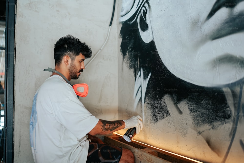 Un uomo sta dipingendo un grande quadro su un muro