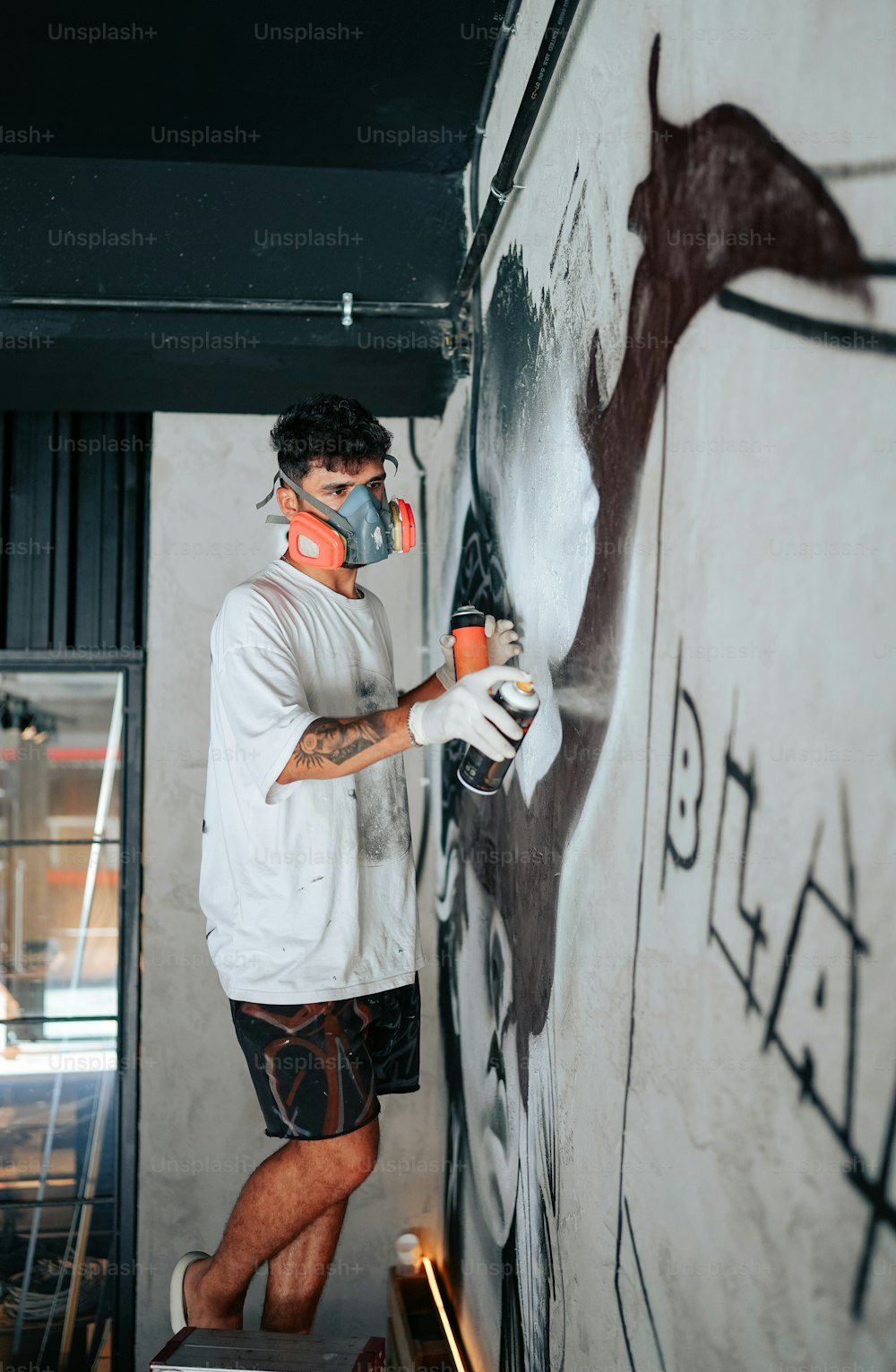 a man spray painting a wall with graffiti