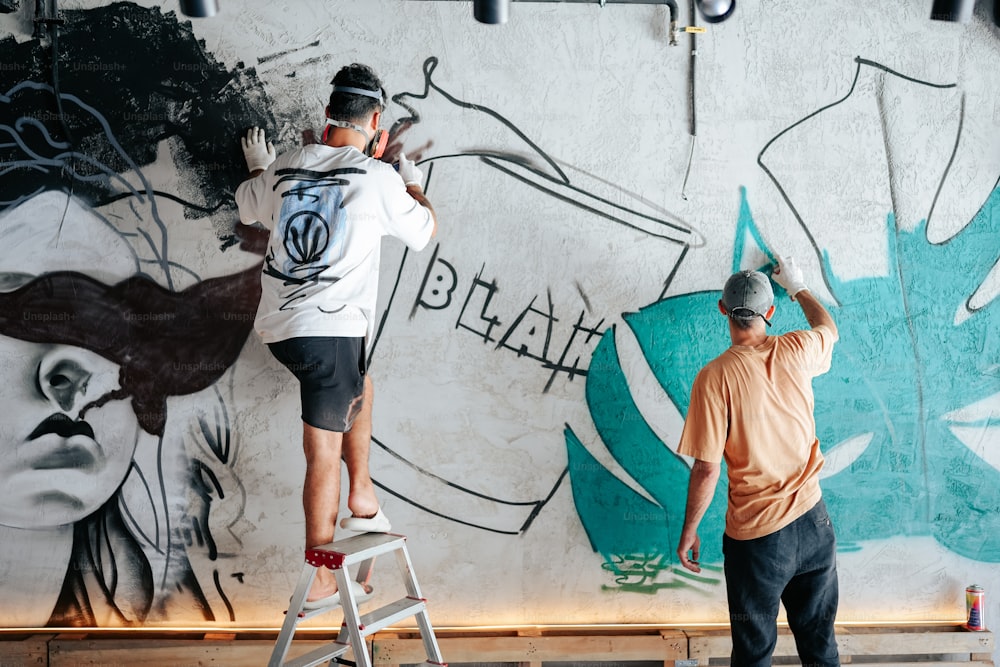two men painting a wall with graffiti on it