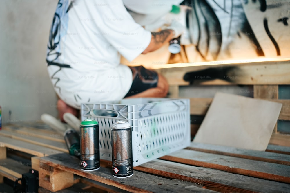 two cans of paint sitting on top of a wooden pallet