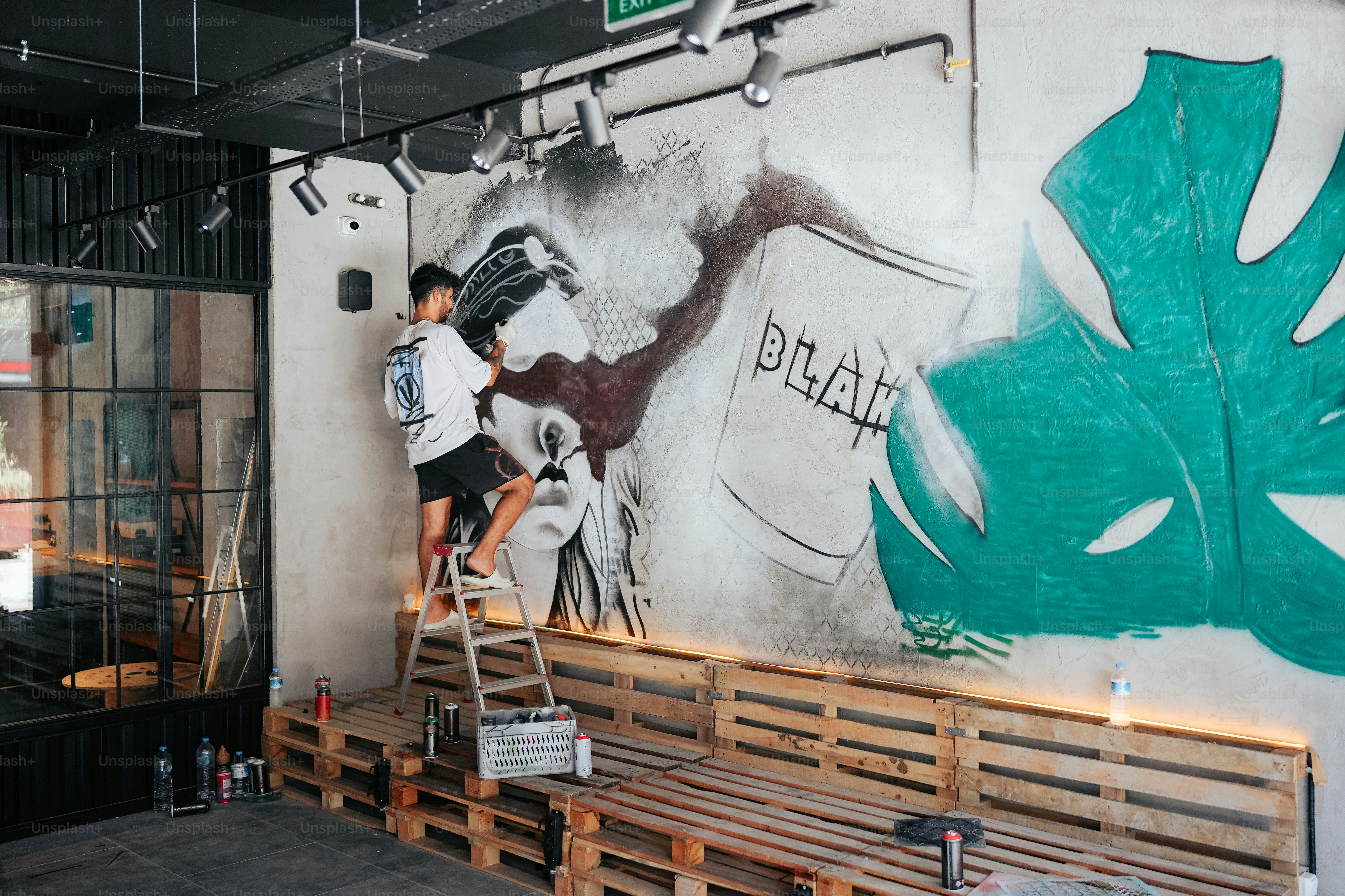 A man is painting a mural on the side of a building photo – Graffiti ...