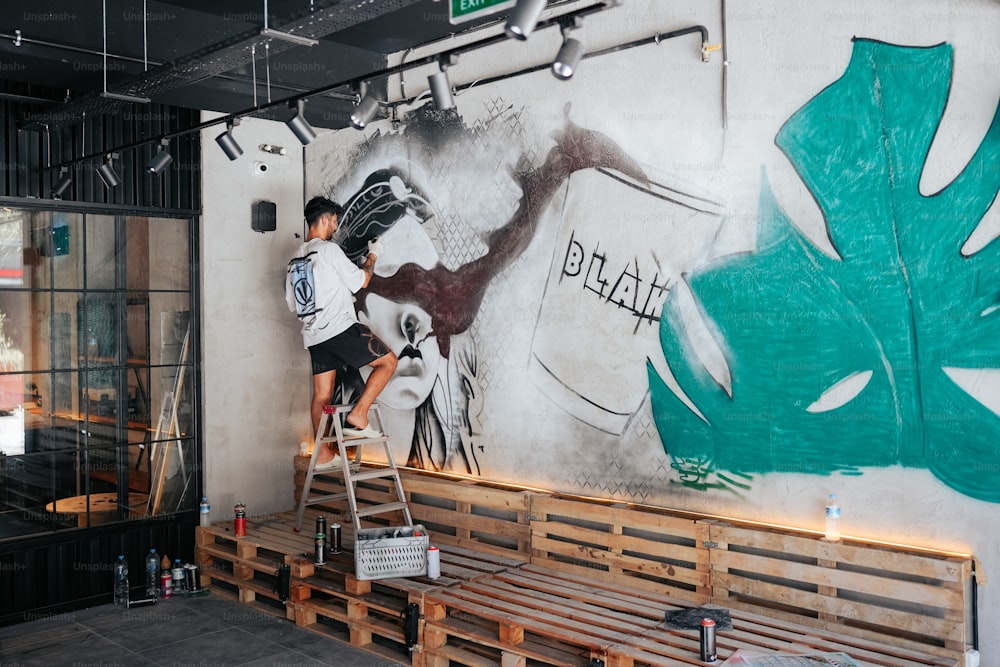 a man is painting a mural on the side of a building