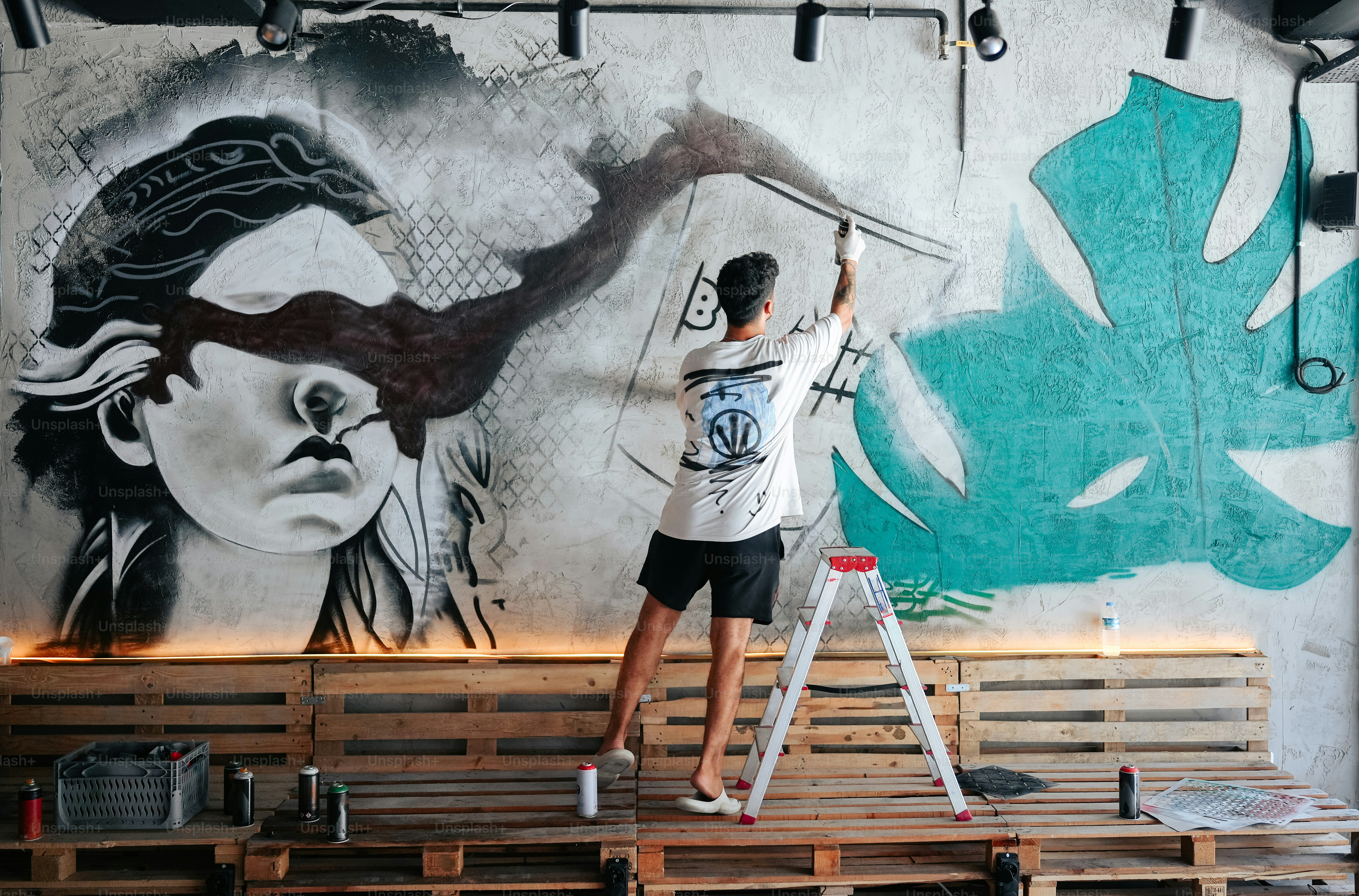 建物の側面に壁画を描く男