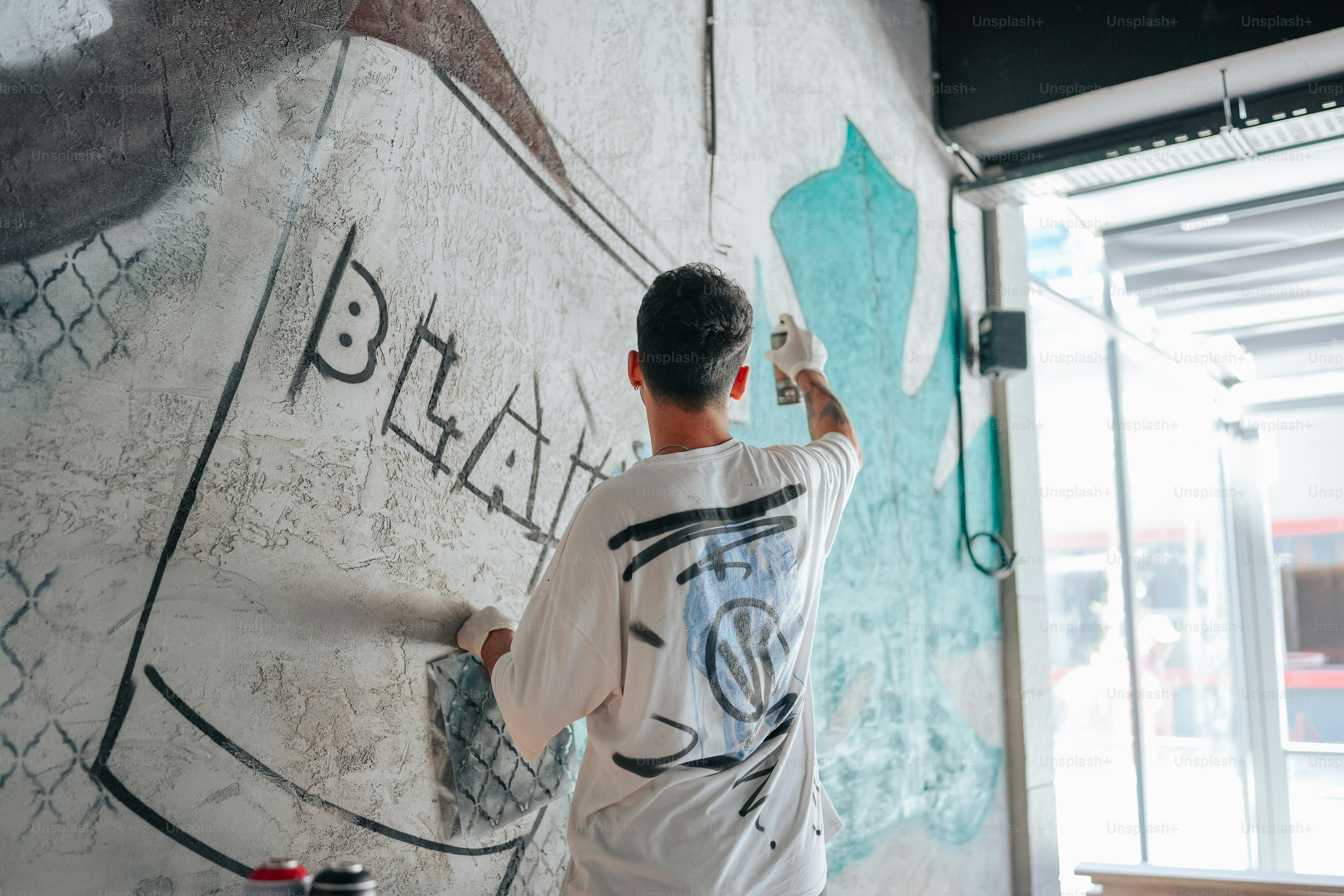 a man painting a wall with graffiti on it
