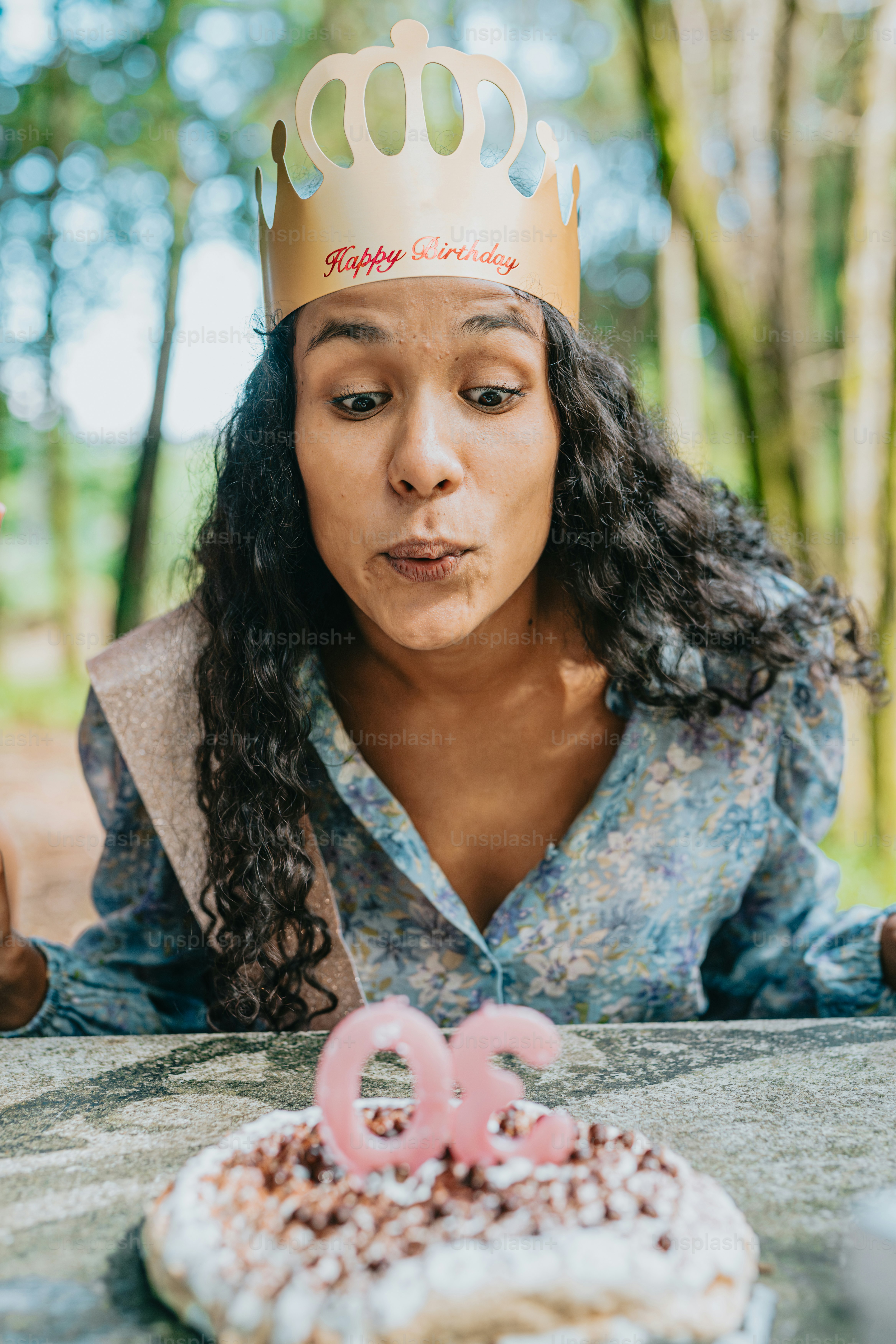uma mulher usando uma tiara soprando as velas em um bolo