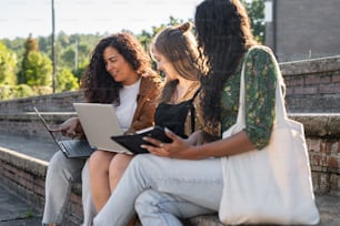 um grupo de mulheres sentadas nos degraus com laptops