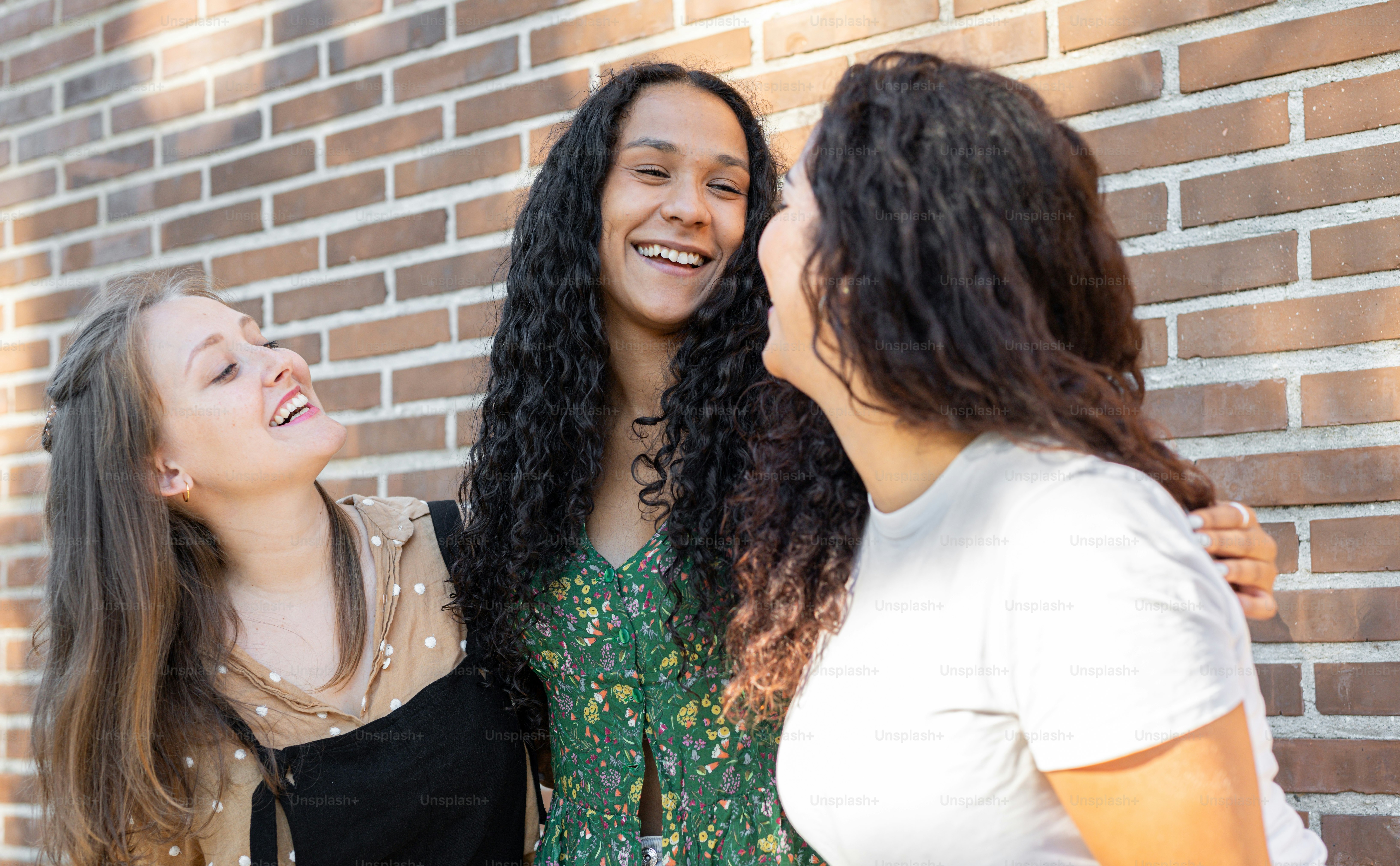 a group of women standing next to a brick wall