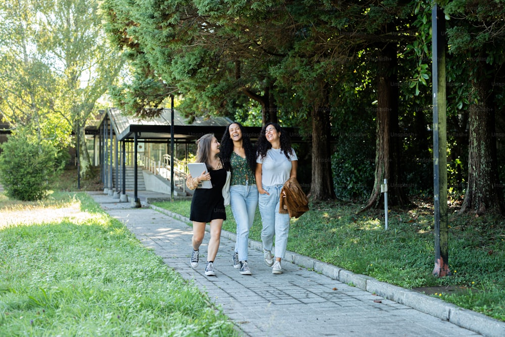 a group of three women walking down a sidewalk