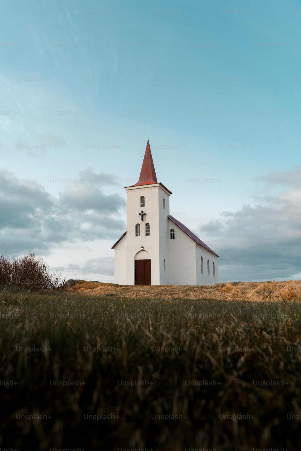 a white church with a red steeple on a hill