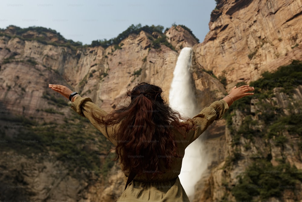 a woman standing in front of a waterfall