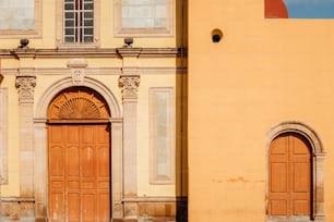 a yellow building with two brown doors and a clock