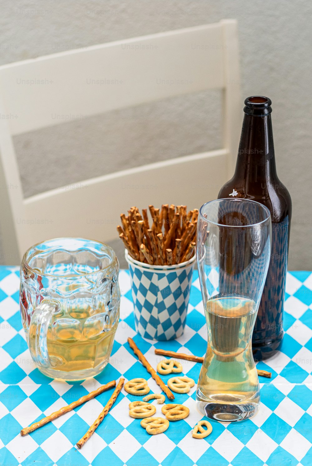 uma mesa coberta com copos de cerveja e pretzels