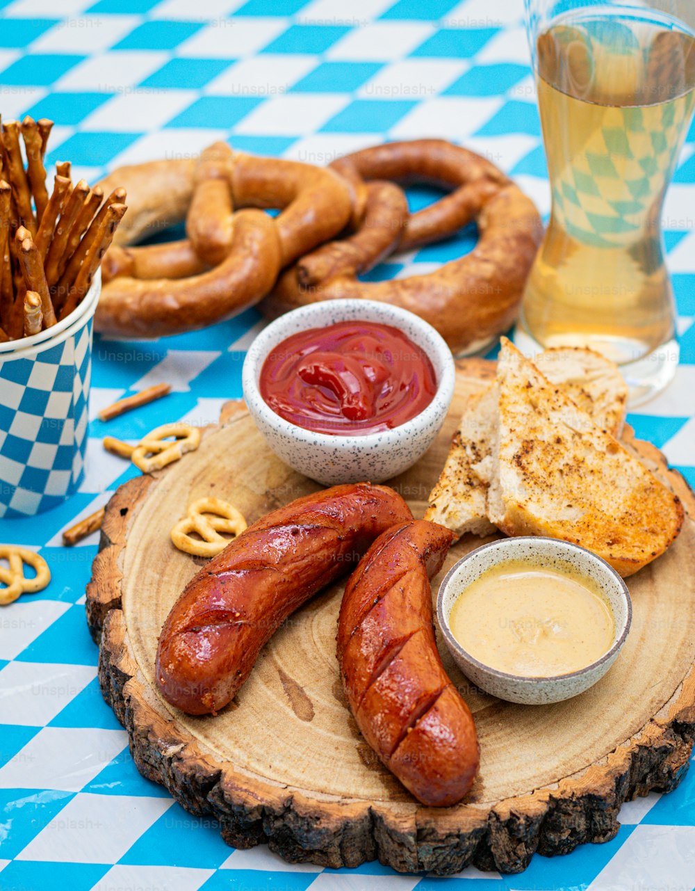 a wooden plate topped with hot dogs and pretzels
