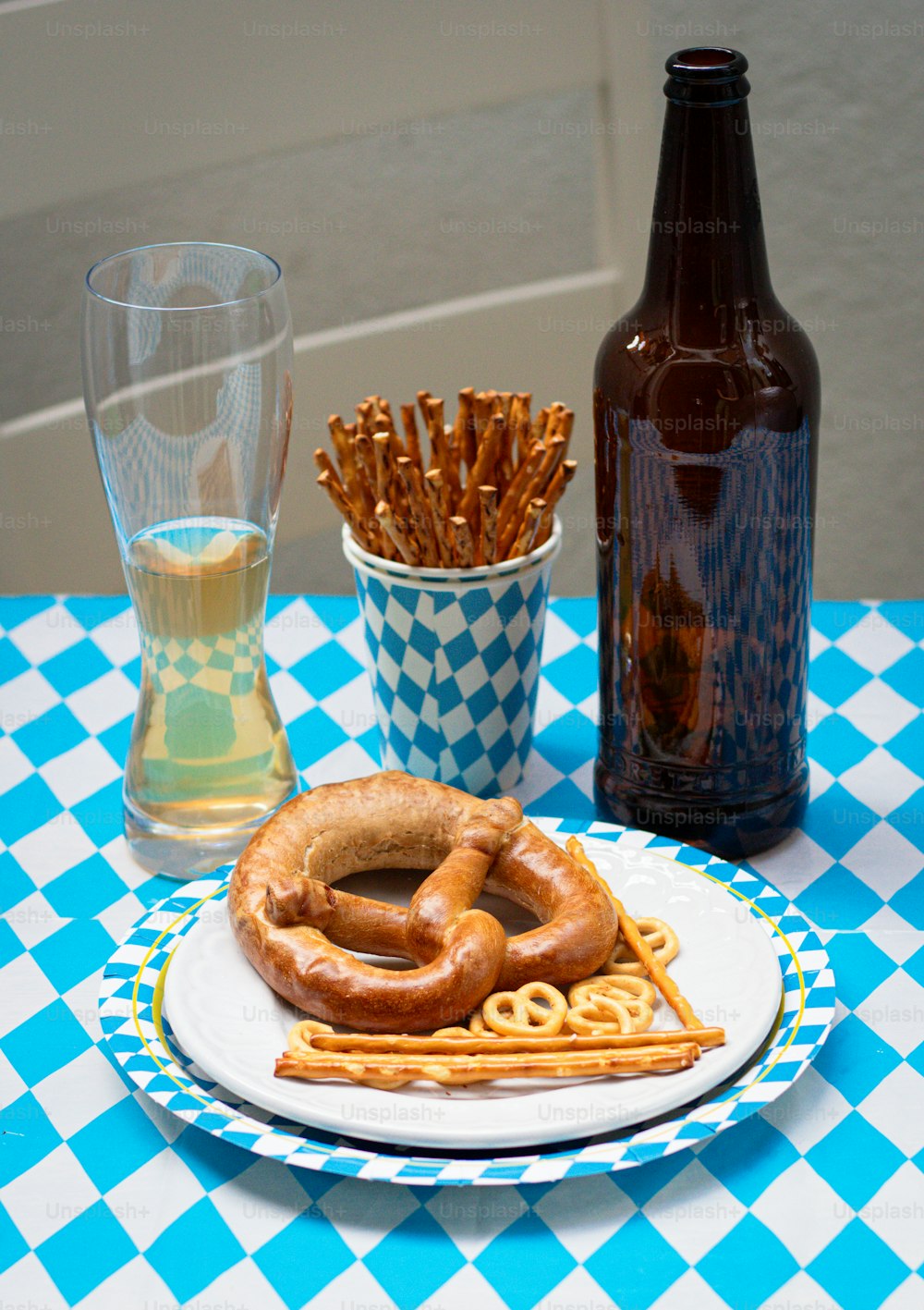 un piatto con un pretzel su di esso accanto a un bicchiere di birra