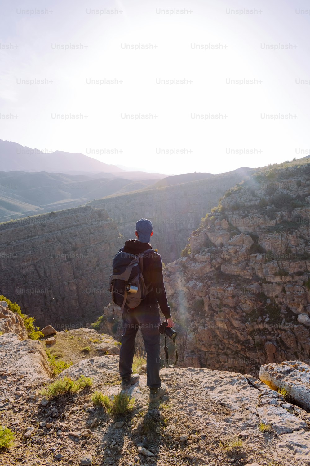 a man with a backpack is standing on a cliff