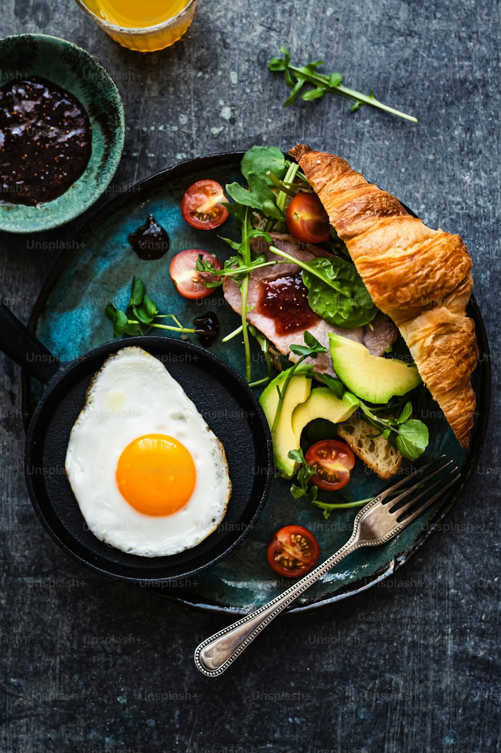 a plate of food with an egg and a croissant