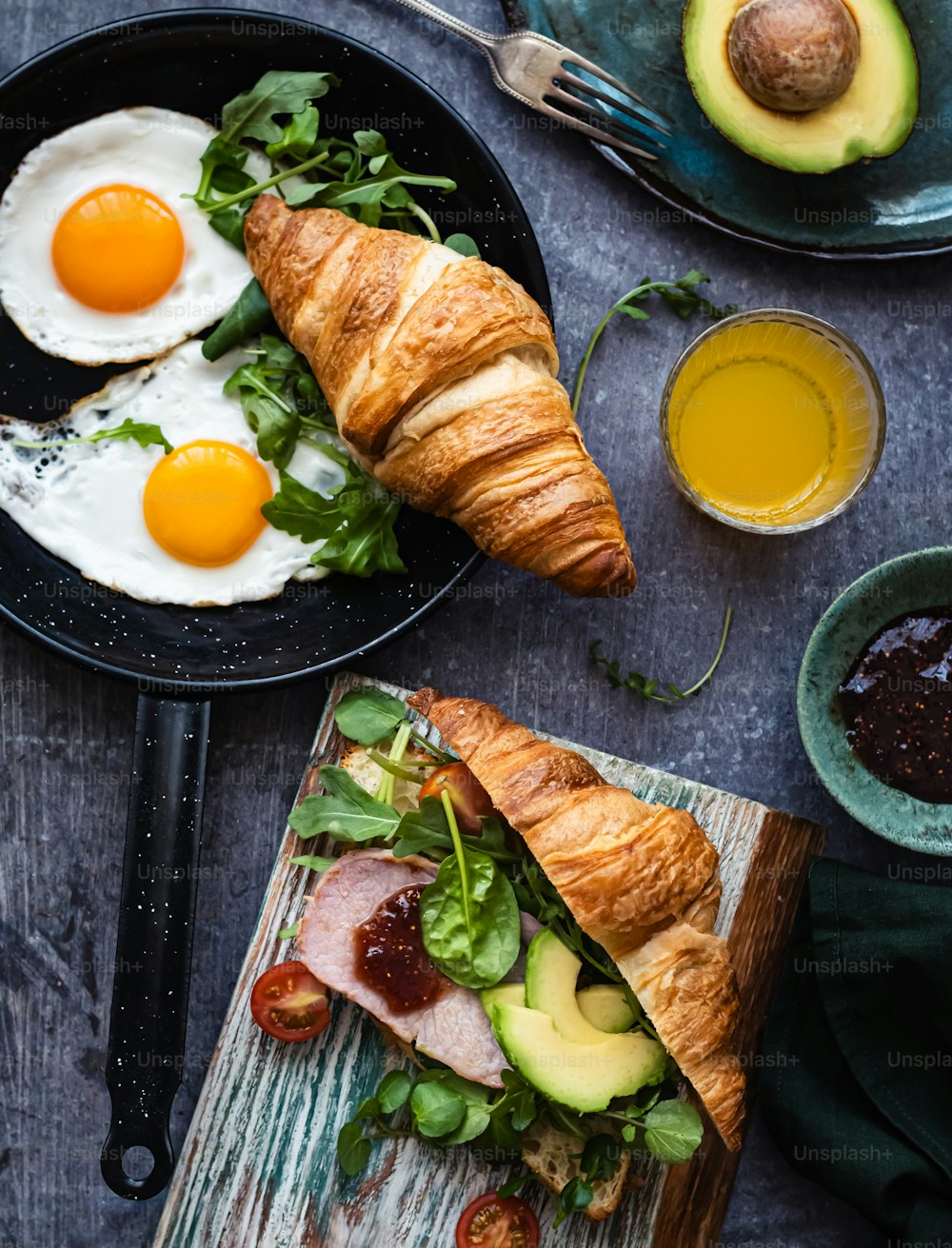 a croissant sandwich with eggs and avocado on a plate