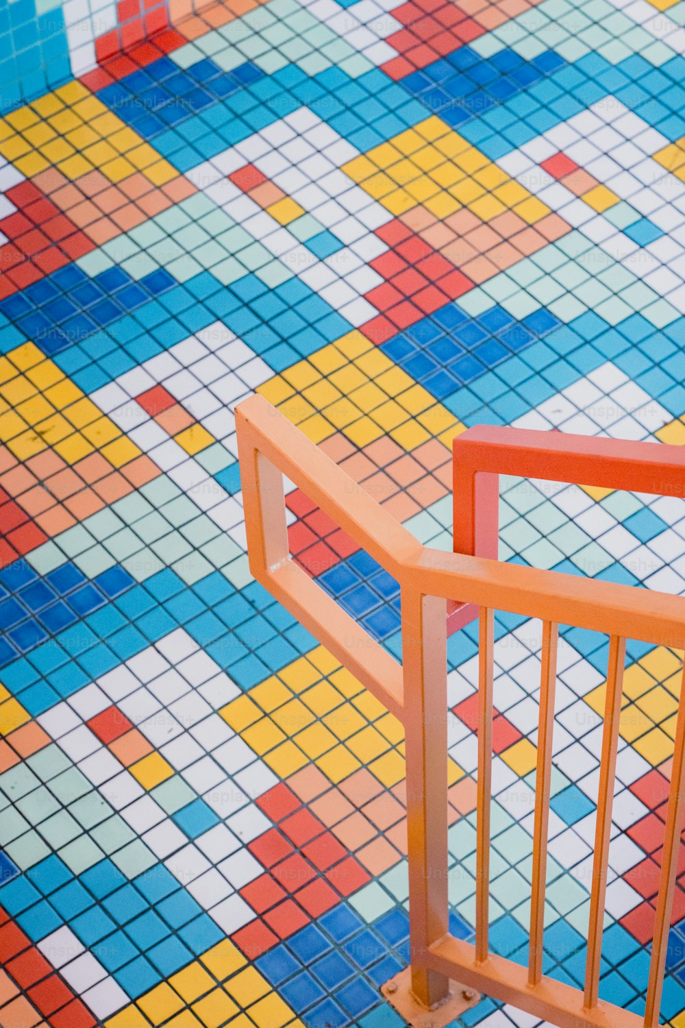 a colorful tiled floor with an orange railing