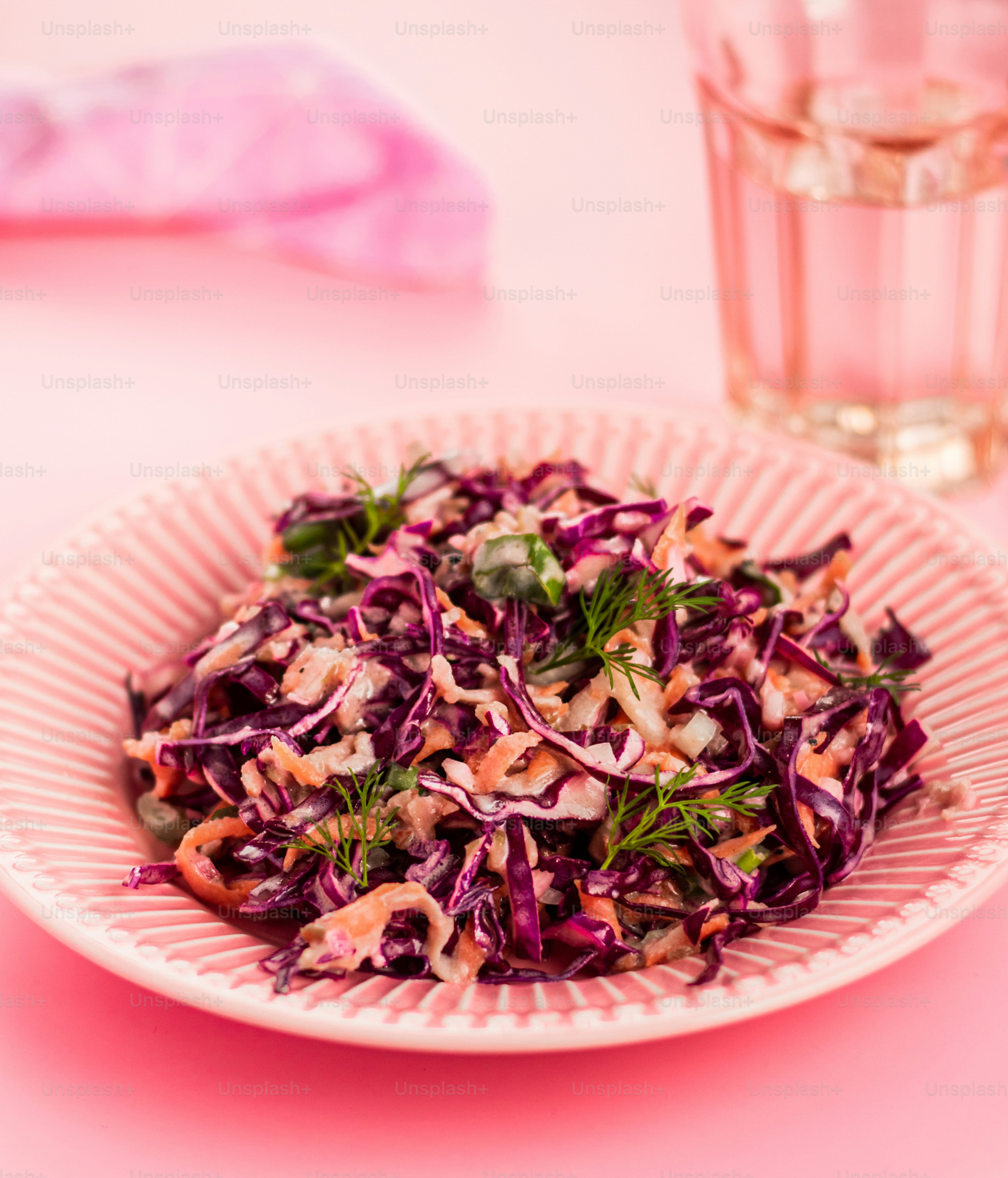 a white plate topped with a asian vegetables next to a glass of water