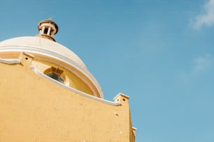a yellow building with a bell tower and a blue sky