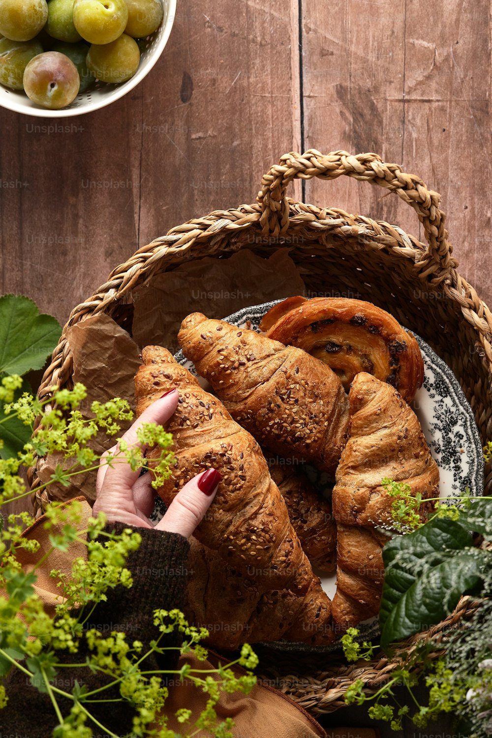 a basket filled with croissants next to a bowl of fruit