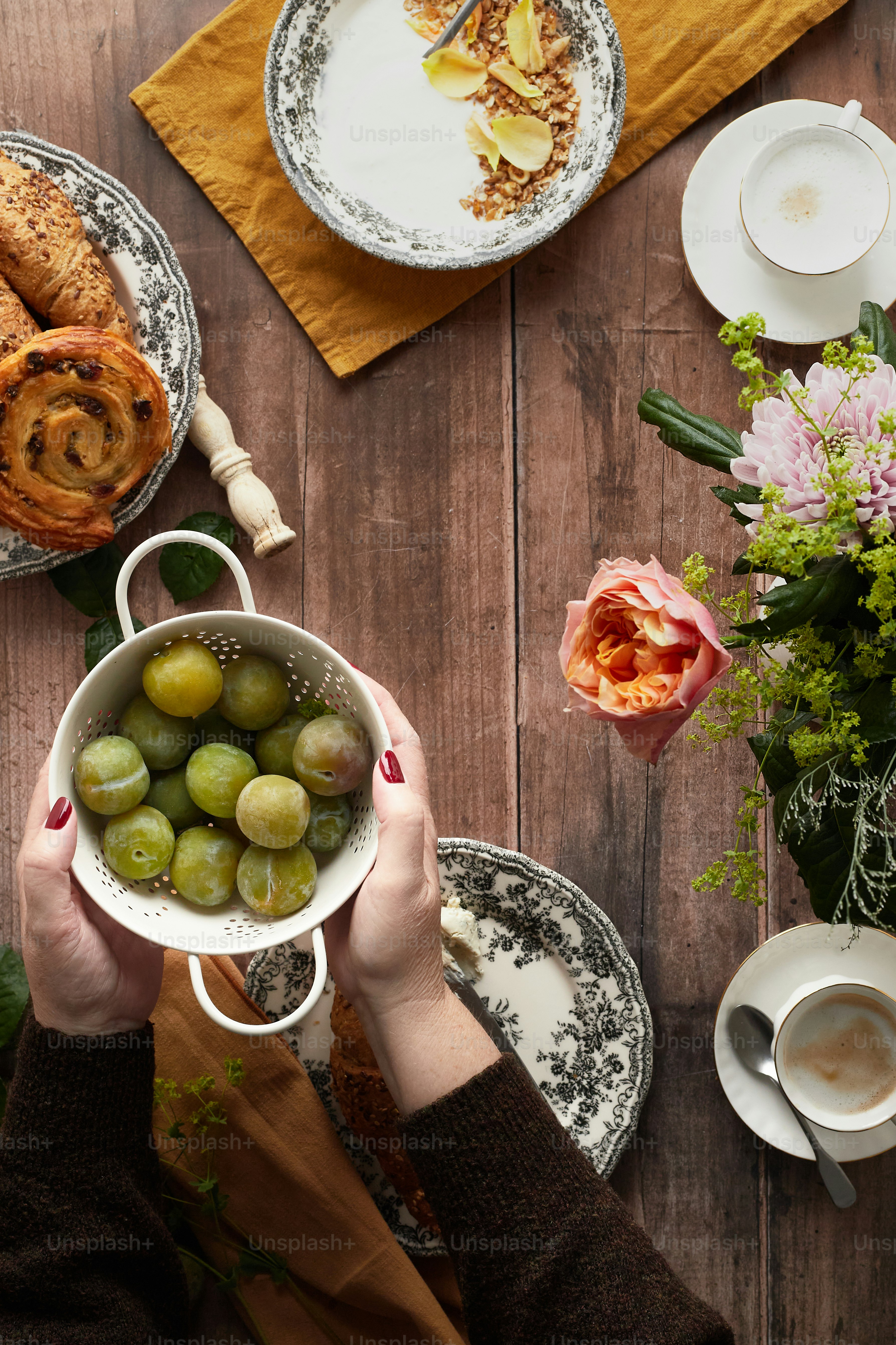 eine Person, die eine Schale mit Trauben auf einem Holztisch hält