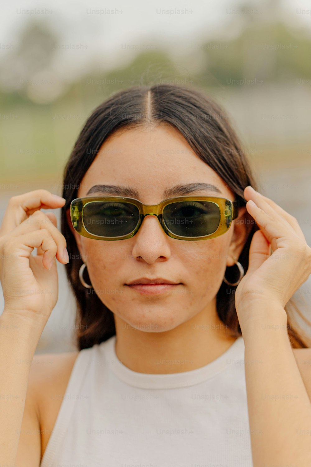 a woman in a white tank top wearing sunglasses