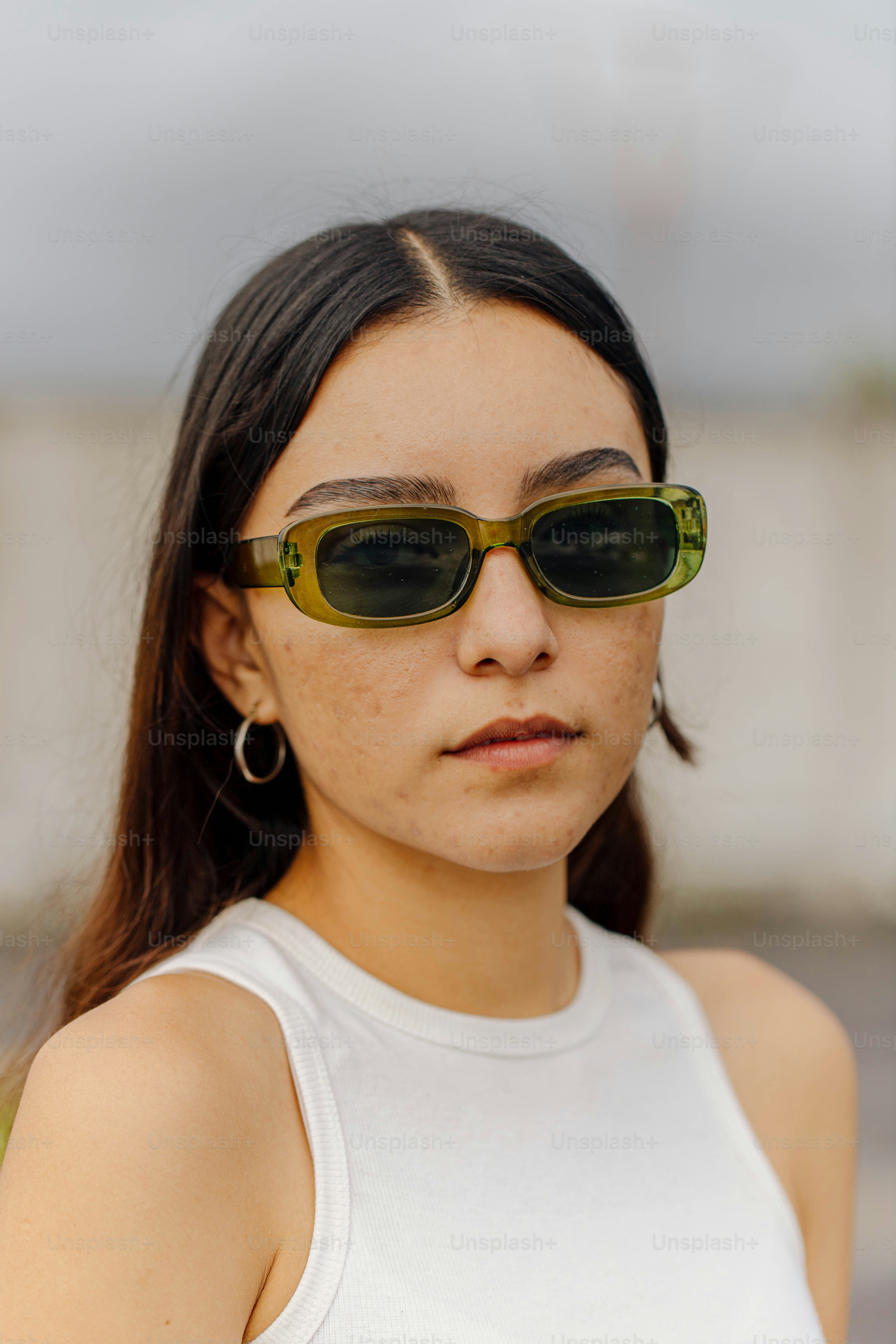eine Frau mit Sonnenbrille und weißem Tanktop