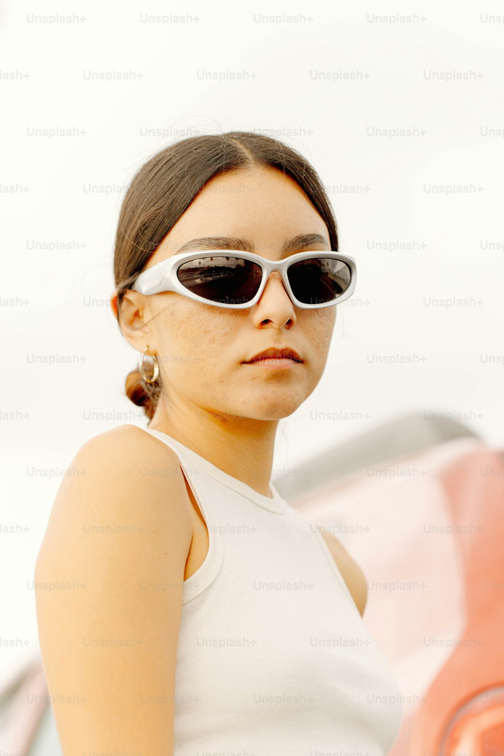 Una mujer con gafas de sol parada frente a un automóvil