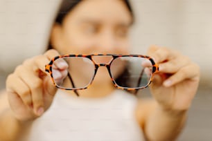 una donna che regge un paio di occhiali