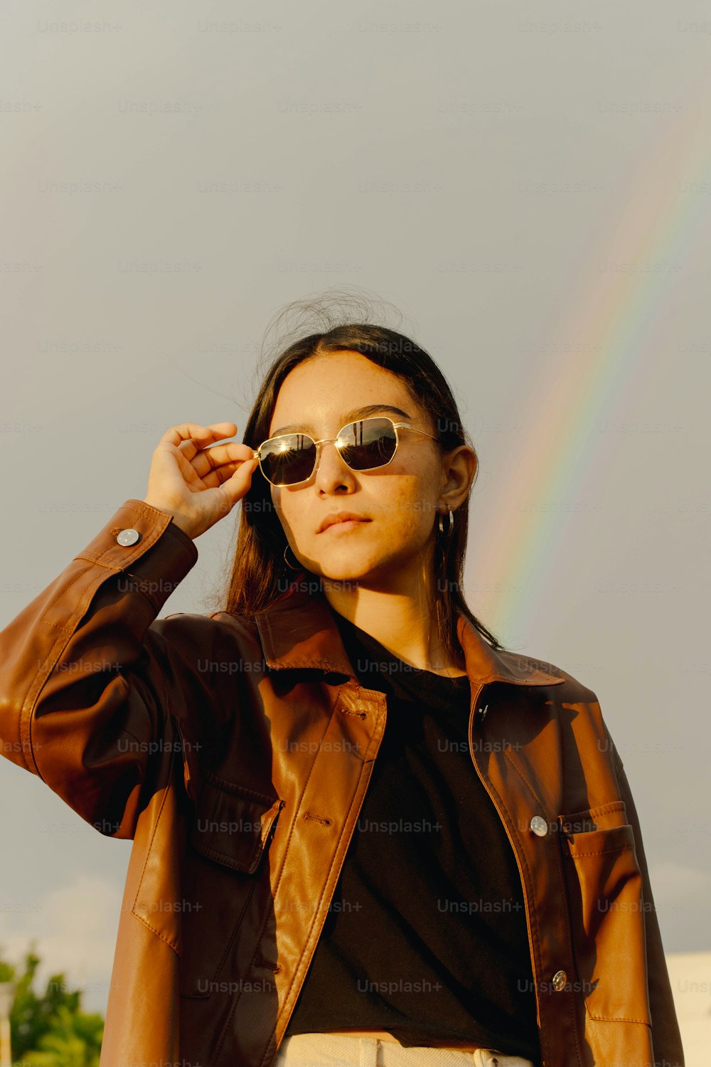 a woman wearing a brown leather jacket and sunglasses