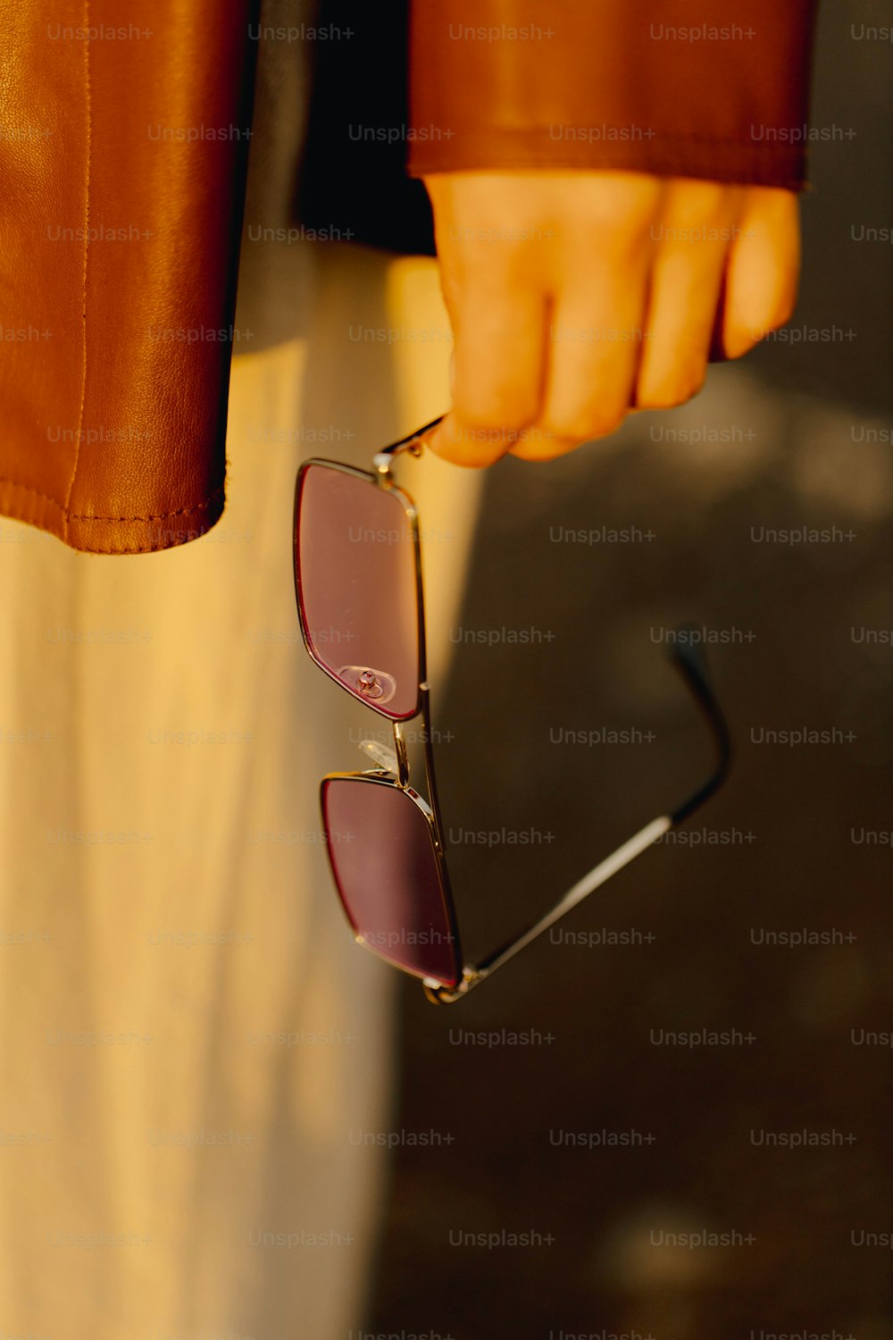 a person holding onto a pair of sunglasses