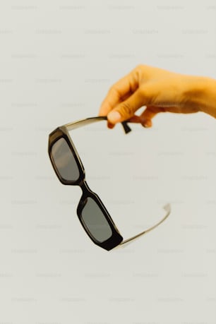 a person holding onto a pair of sunglasses