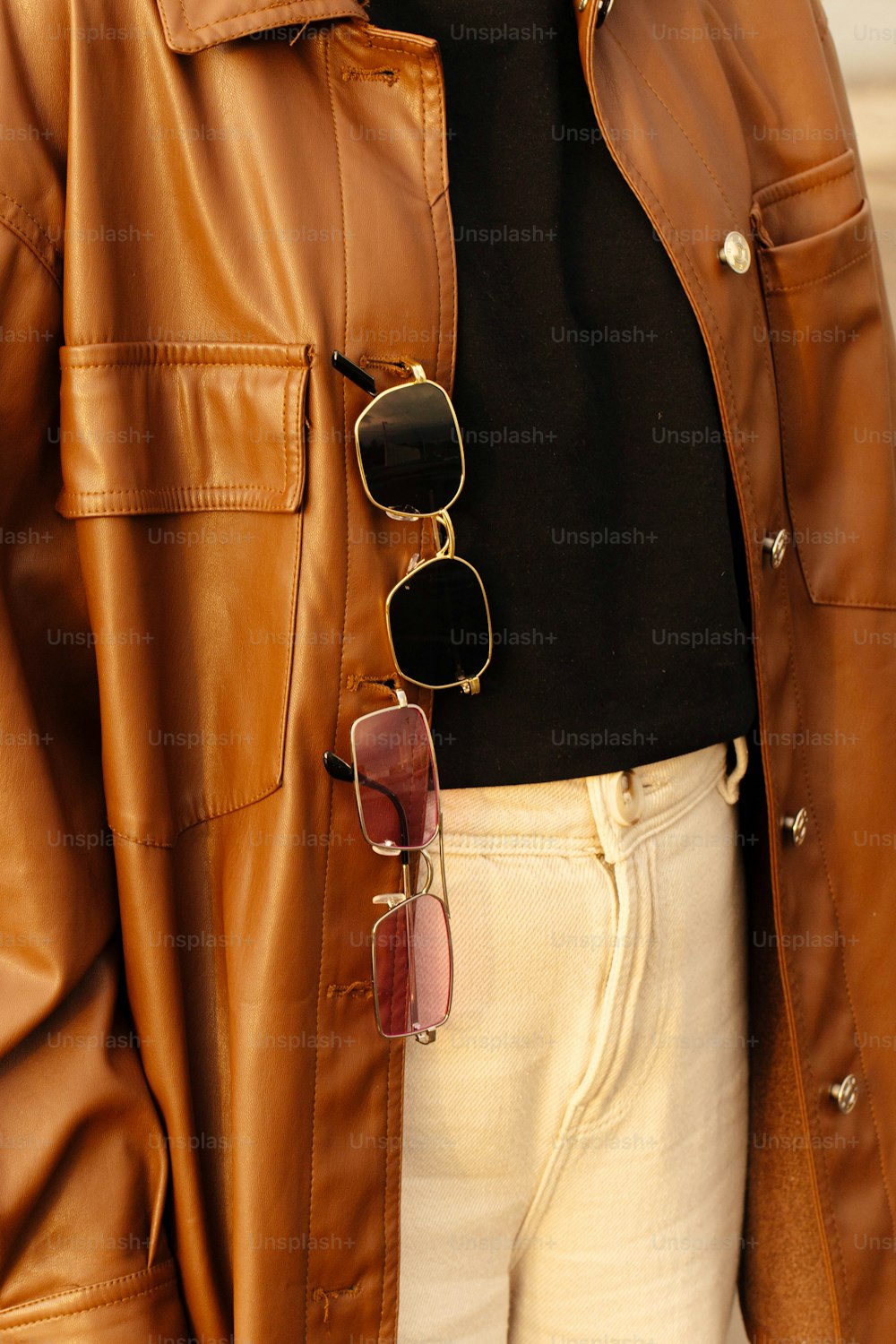 a woman wearing a brown leather jacket and sunglasses