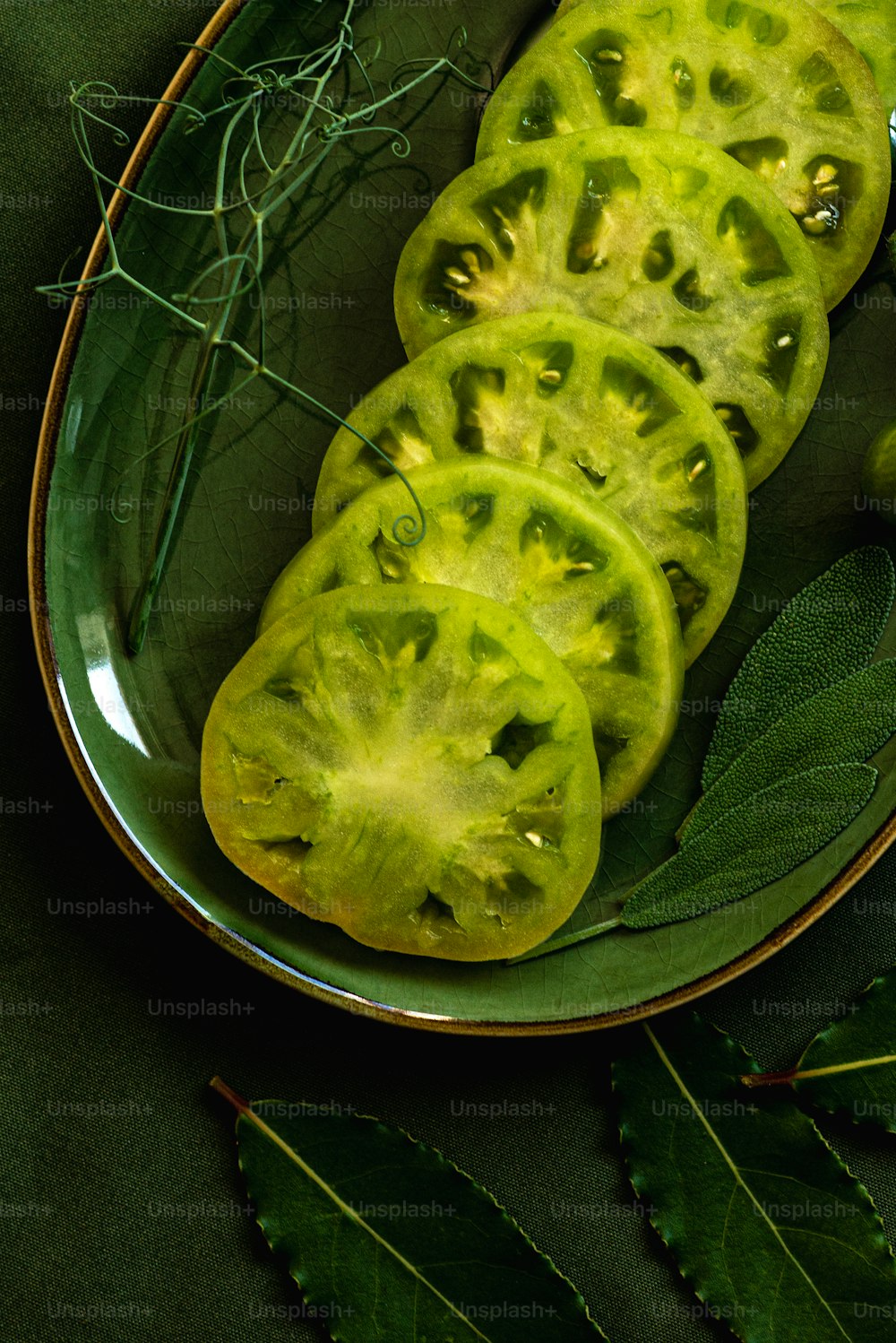 a plate of sliced green tomatoes with leaves