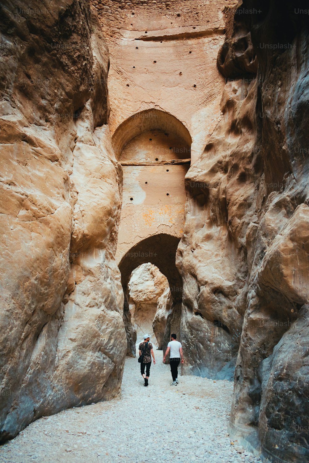 a couple of people walking through a narrow tunnel