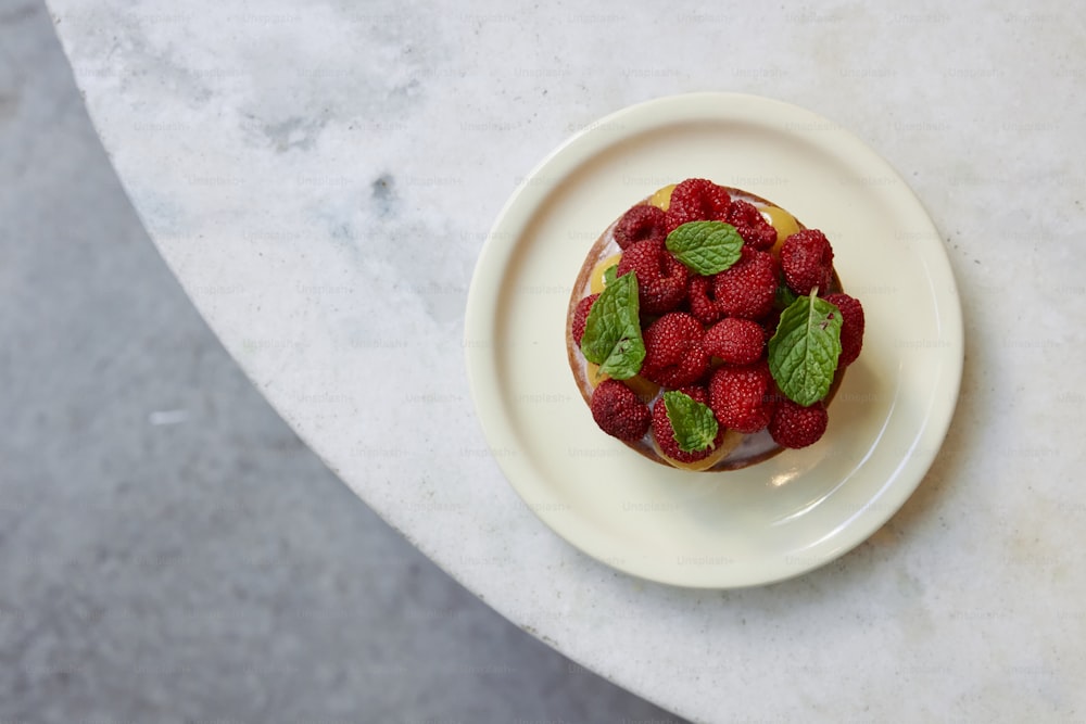 a plate with a dessert topped with raspberries and mint
