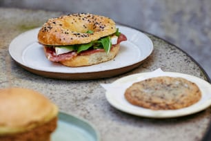 a bagel sandwich on a plate next to a bagel
