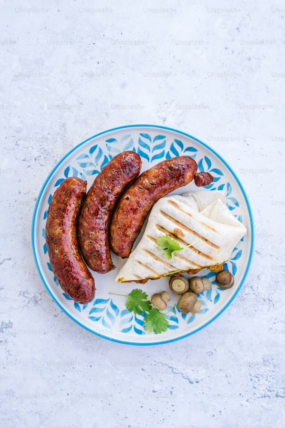 a blue and white plate topped with sausages and cheese