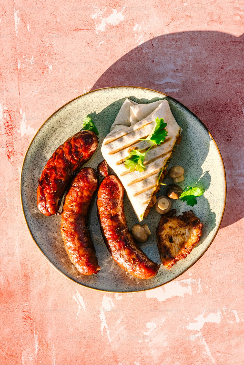 a plate of sausages, bread, and vegetables on a table