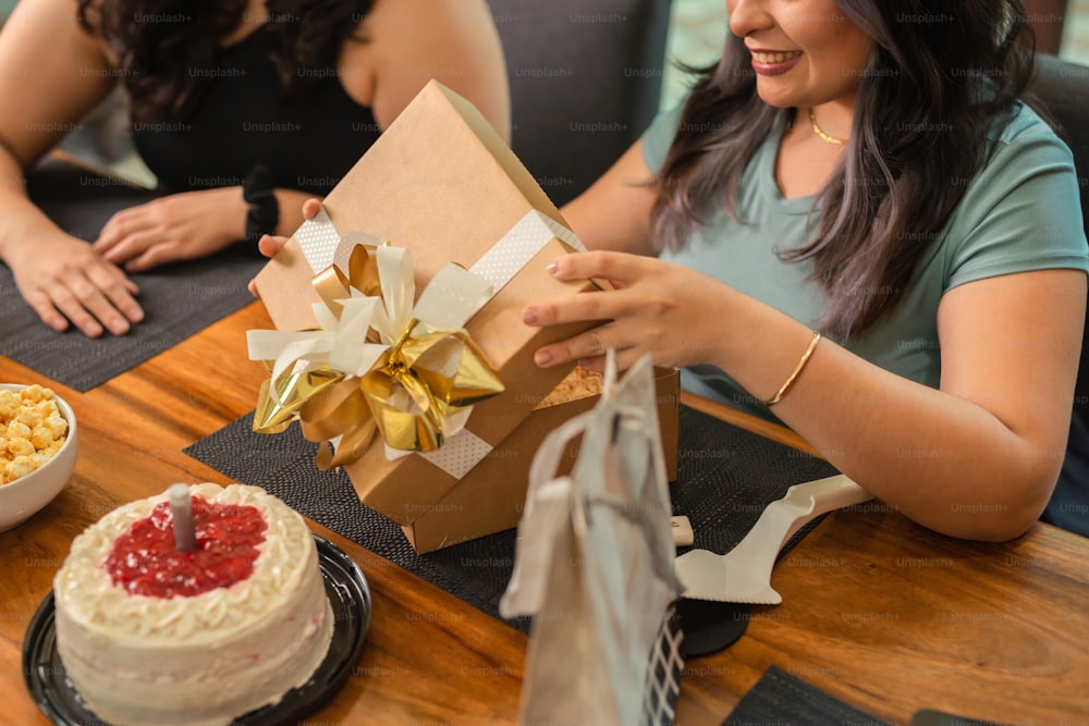 two women sitting at a table with a cake and a box