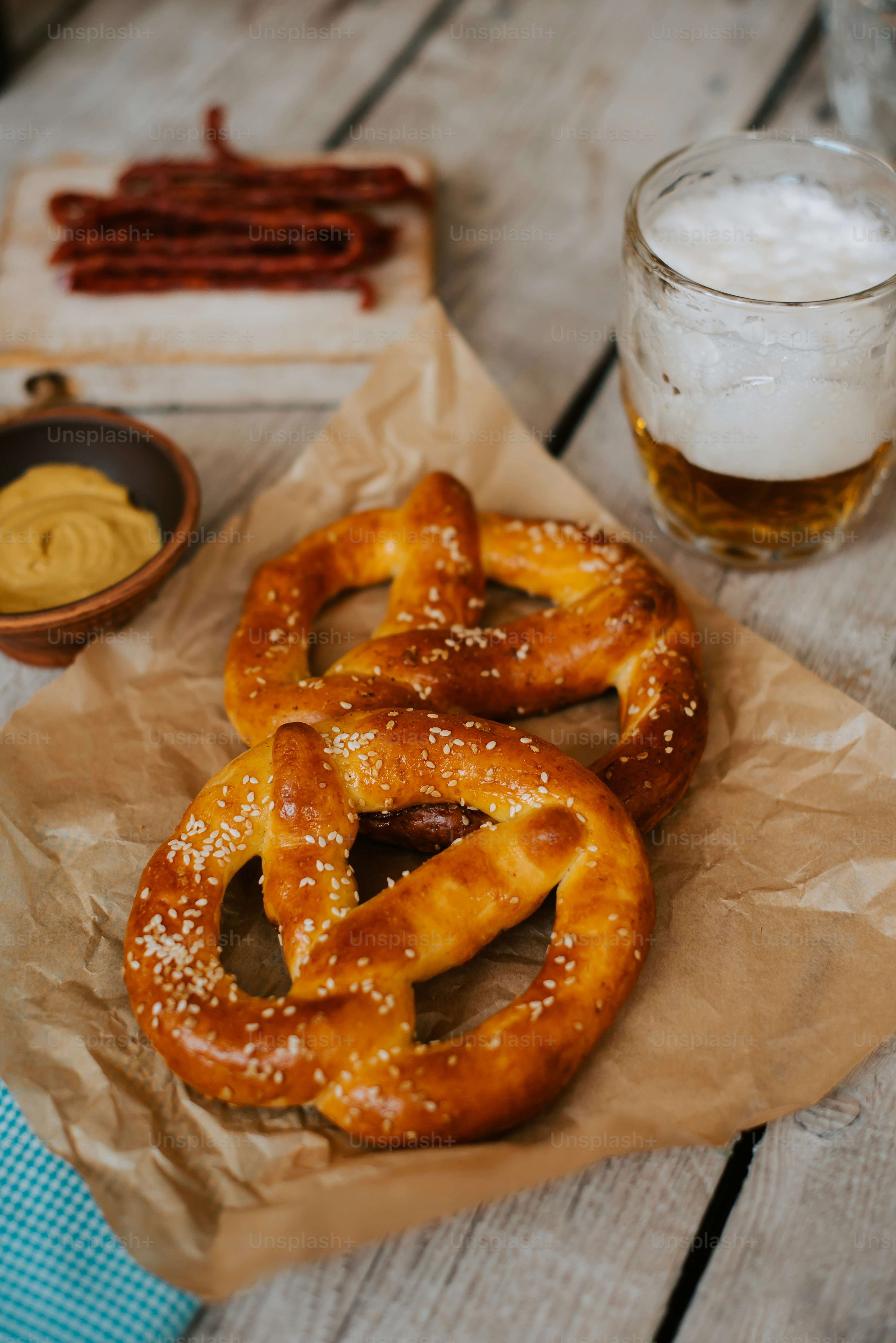 two pretzels on a piece of wax paper next to a glass of beer