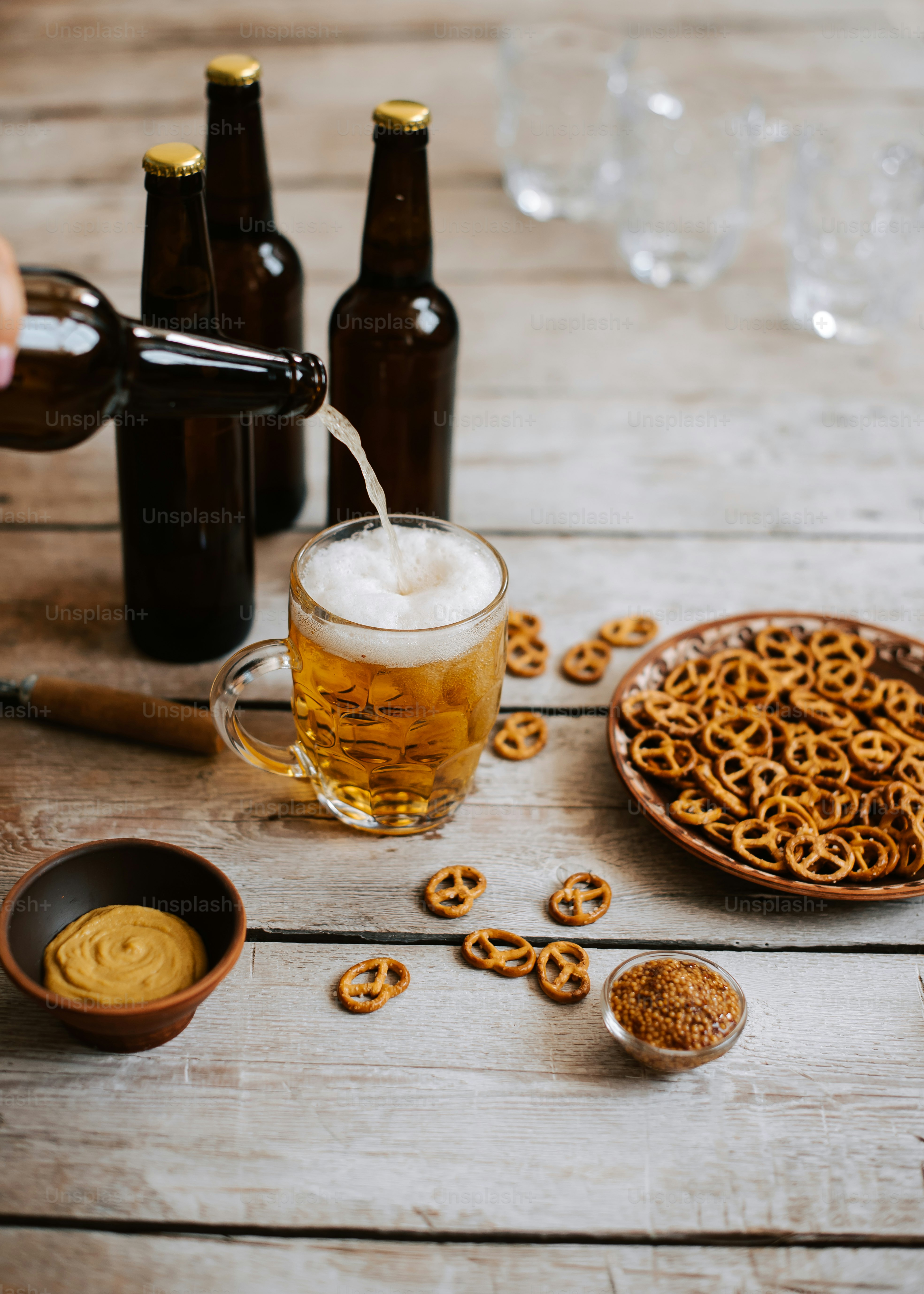 Une personne verse de la bière dans une tasse entourée de bretzels