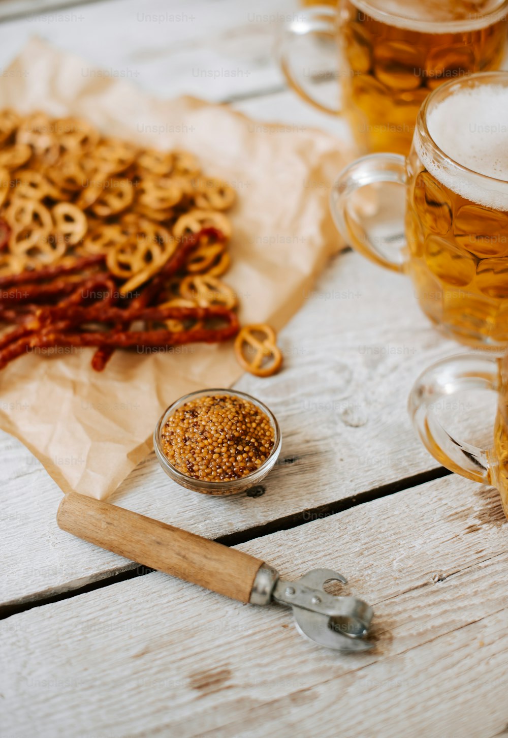 a table topped with mugs of beer and pretzels