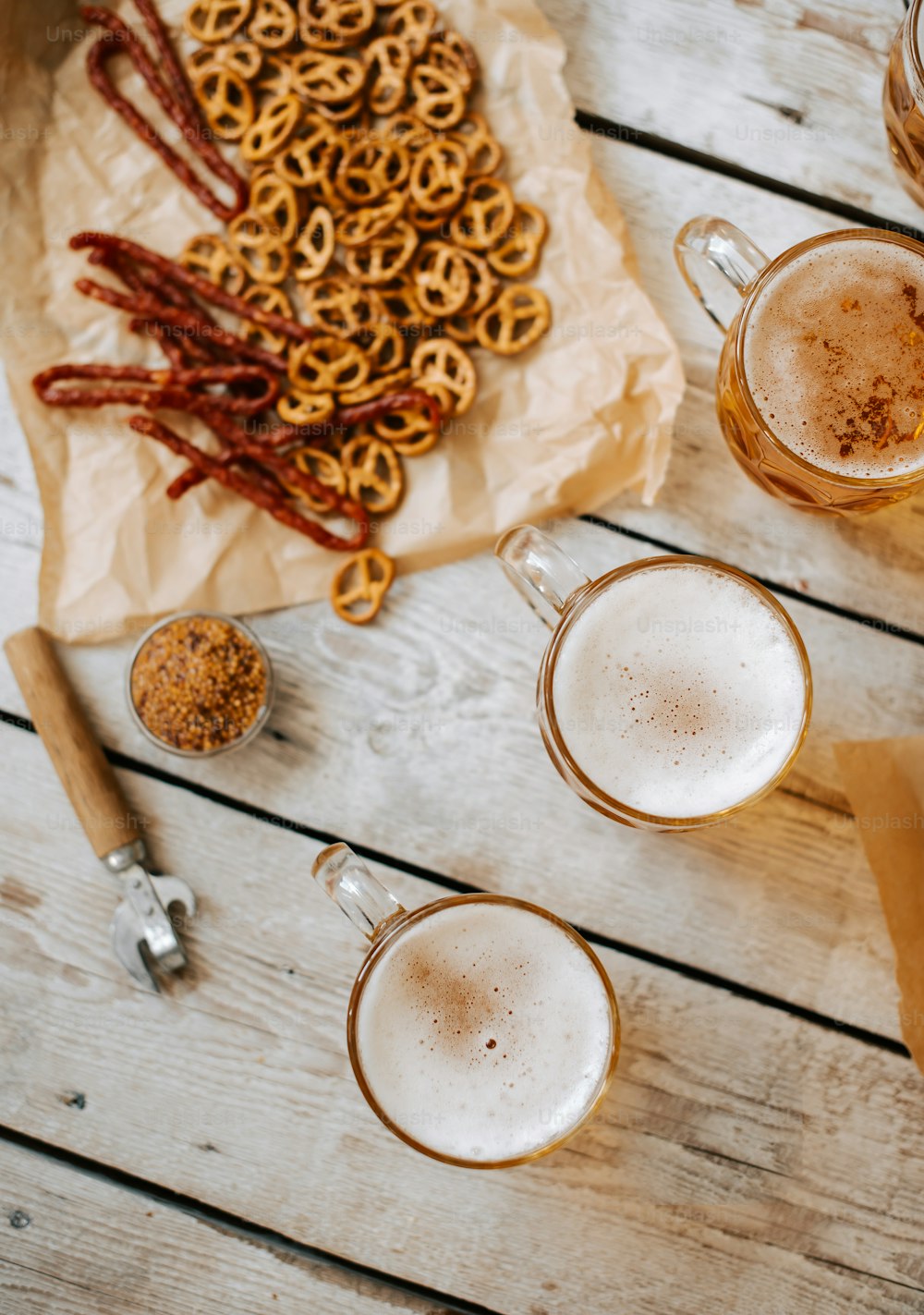 two mugs of beer and some pretzels on a table