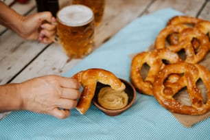 a person holding a pretzel over a bowl of dip