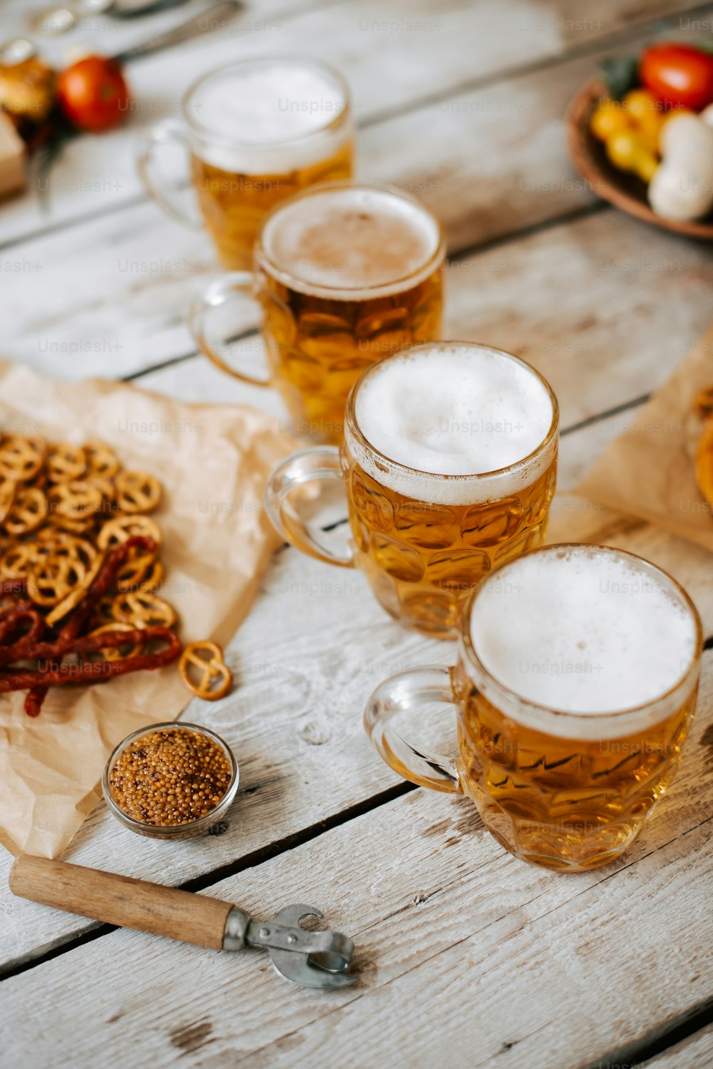 uma mesa coberta com canecas de cerveja e pretzels