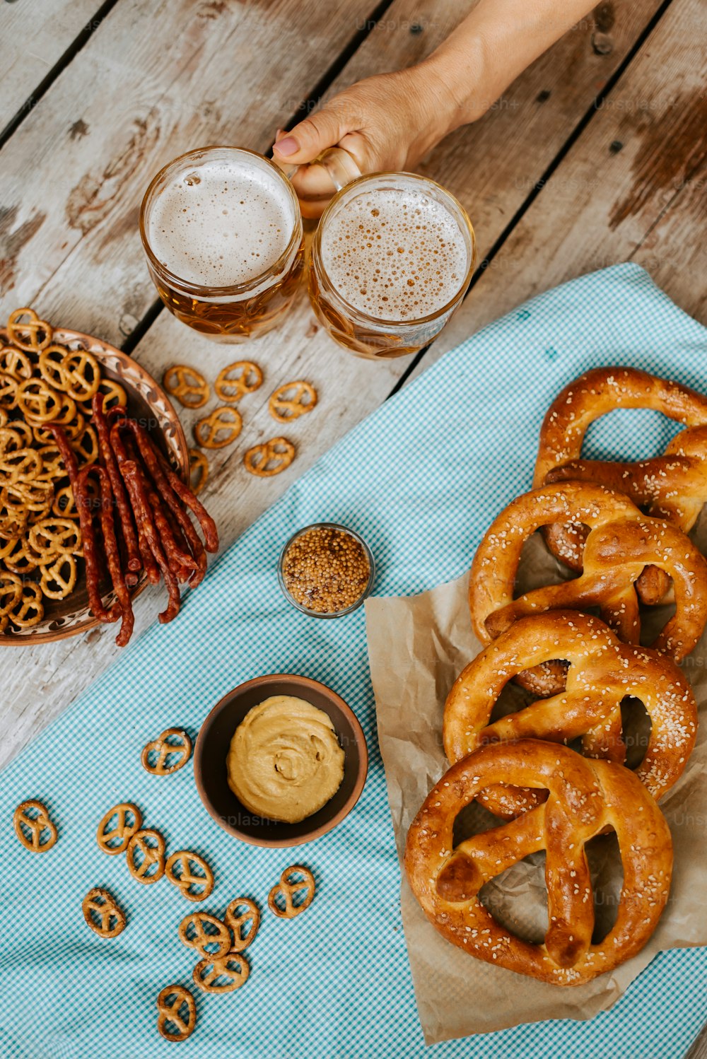 a table topped with pretzels next to two mugs of beer
